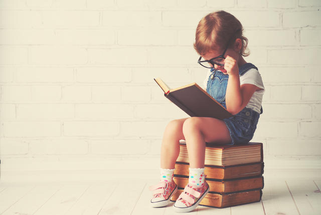 child little girl with glasses reading a books