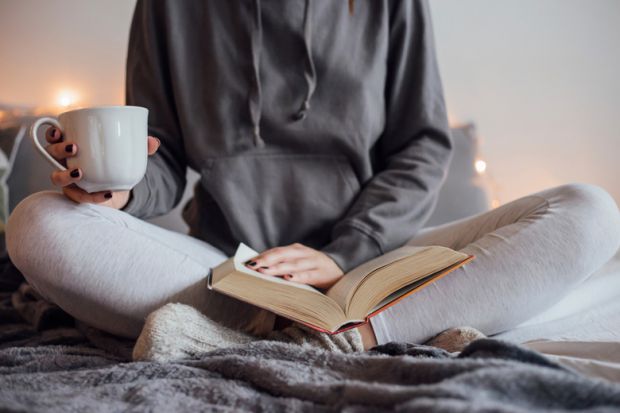 woman-reading-book-and-drinking-tea-on-bed