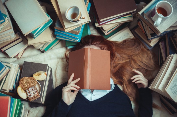 Girl sleeping near  books with and cups of tea